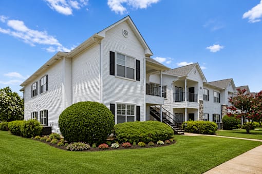 A white two-story house with a well-manicured lawn and a clear blue sky.