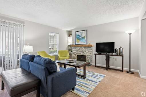 A living room with a blue couch, a fireplace, and a television.
