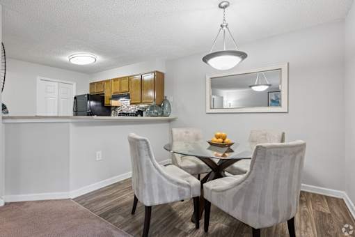 A dining room with a glass table and four chairs.