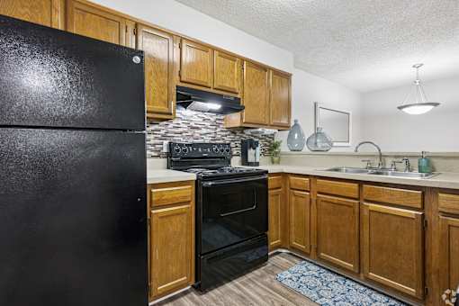A black fridge in a kitchen with wooden cabinets.