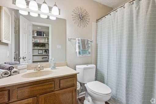 A bathroom with a toilet, sink, and shower curtain.