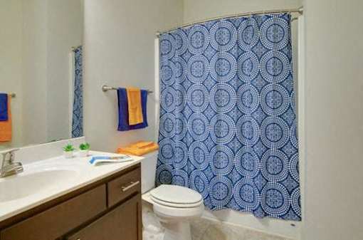 A bathroom with a toilet, sink, and shower curtain.