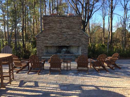 A stone fireplace with chairs around it.