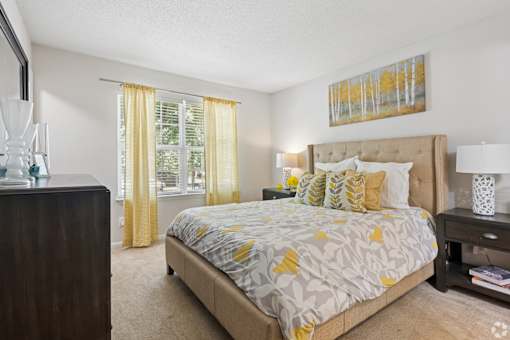 A bedroom with a bed, nightstand, and a painting on the wall.