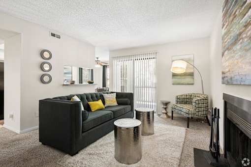 A black couch with yellow pillows is in the center of a living room.