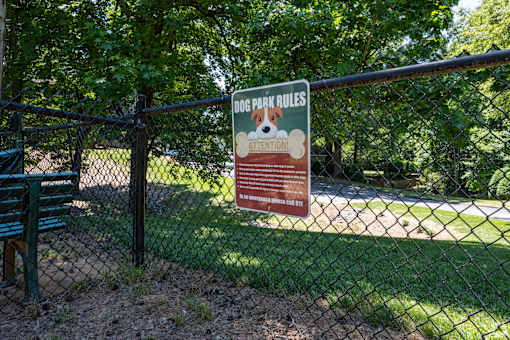 A sign on a fence that says Dog Park Rules.