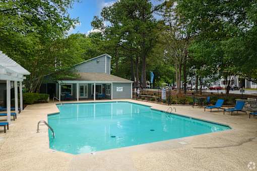A small pool surrounded by trees and a building.