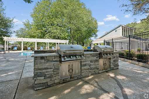 A stone grill is in the middle of a patio.