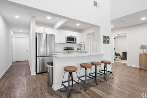 A kitchen with a bar and stools in the middle of the room.