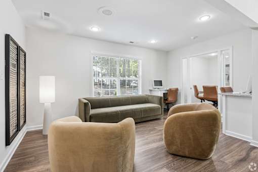 A living room with a couch, two chairs, and a table.