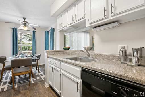 A kitchen with a black dishwasher and a fan.