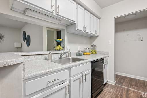 A kitchen with white cabinets and a marble countertop.