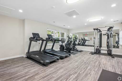 A spacious gym with treadmills, elliptical machines, and a weight rack.