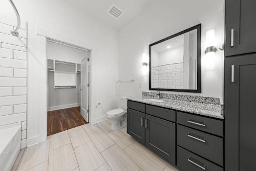 A bathroom with a toilet, sink, and a mirror.