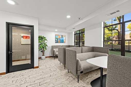 A modern waiting room with grey couches and a black table.