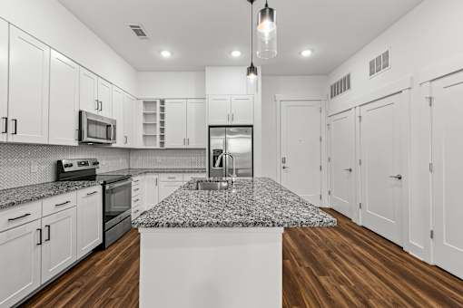A kitchen with white cabinets and a granite countertop.