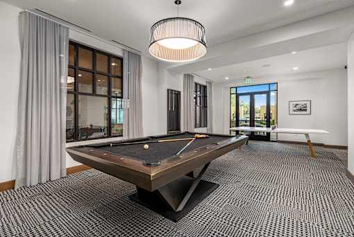 A pool table is in the middle of a room with a carpeted floor.