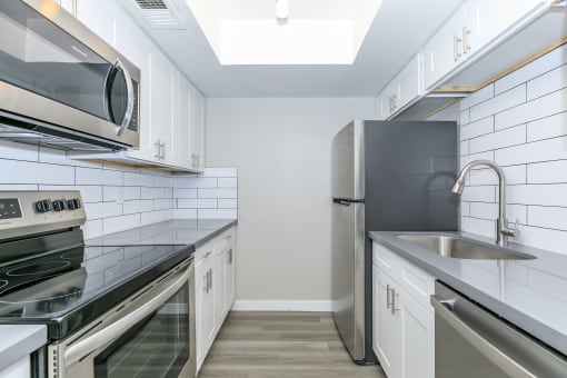 a kitchen with stainless steel appliances and white cabinets at Tides on Southern, Mesa, AZ 85204