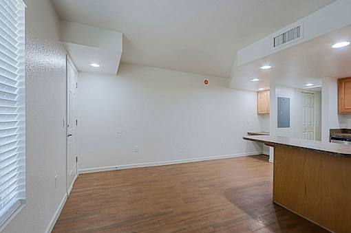 A room with a wooden floor and a white ceiling with a vent.