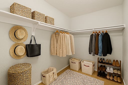 A white closet with clothes and shoes.