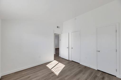 an empty room with white walls and wood floors
