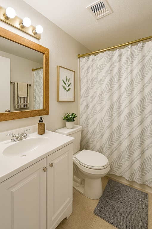 A bathroom with a white toilet, sink, and shower curtain.