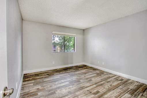 A room with wooden flooring and a window.