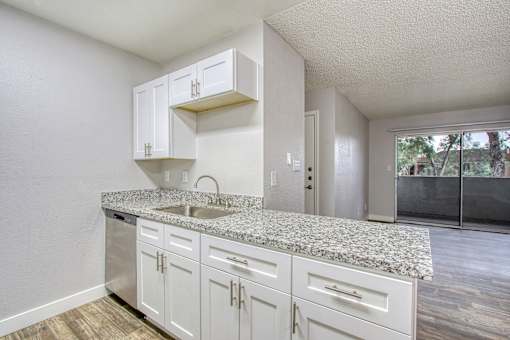 A kitchen with white cabinets and granite countertops.