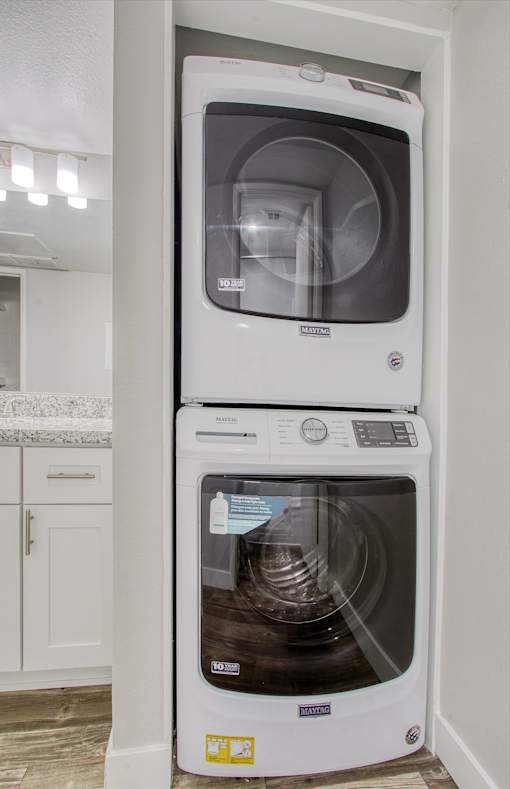 A white dishwasher is stacked on top of a white microwave in a kitchen.