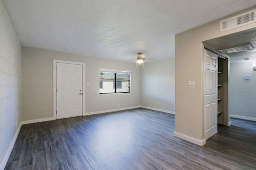A room with a white door, a window, and a wooden floor.
