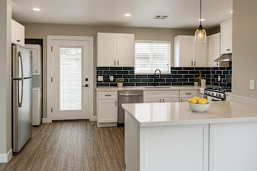 A kitchen with white cabinets and a black backsplash.