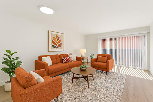 A living room with orange furniture and a painting on the wall.