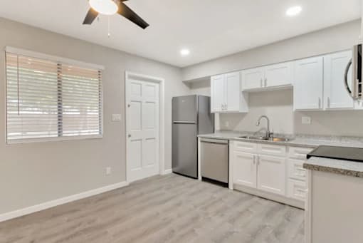 an empty kitchen with white cabinets and a stainless steel refrigerator
