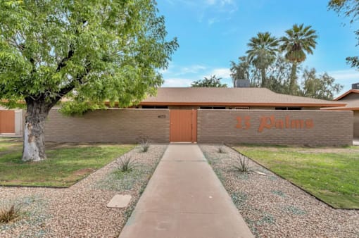 a house with a tree and a sidewalk in front of it