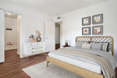 A bedroom with a large bed and a dresser with a mirror at Foothills Court Apartments, Phoenix, AZ 85029