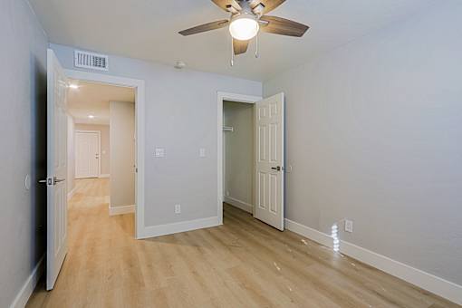 an empty room with a ceiling fan and a door to a closet