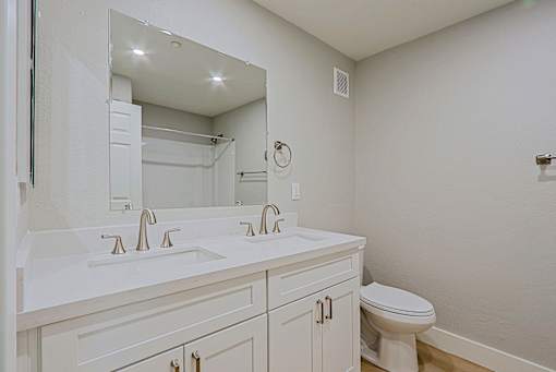 a bathroom with a large mirror and a sink and a toilet