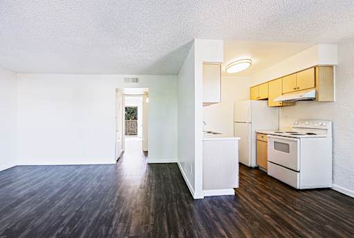 A kitchen with white appliances and wooden floors.
