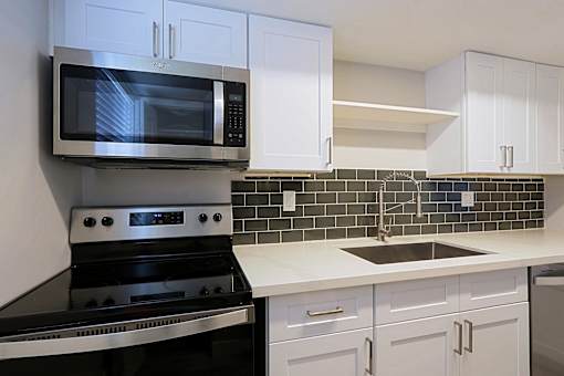 A modern kitchen with white cabinets and black appliances.