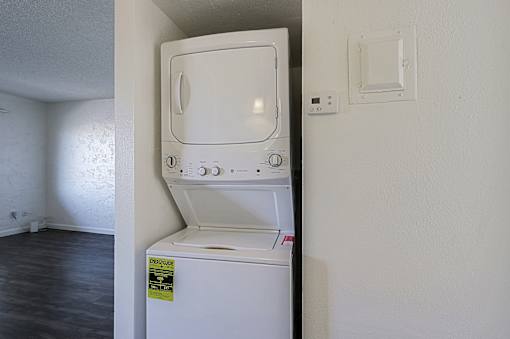 A white dishwasher with a yellow caution label on the door is in a room with white walls.
