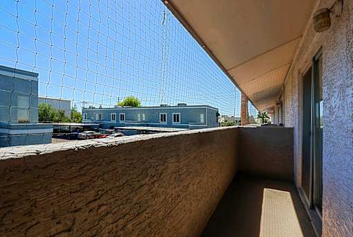 A balcony with a netting over it and a building in the background.