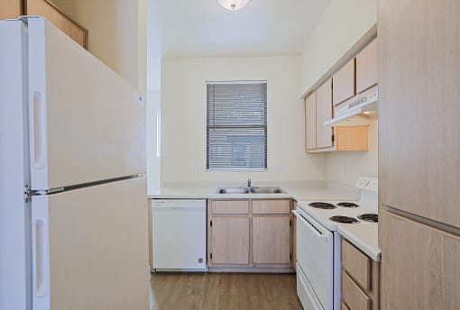 an empty kitchen with white appliances and wooden cabinets