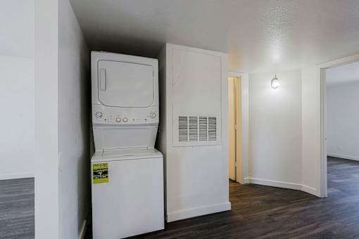 A white arcade machine sits in a room with a white wall and a door.