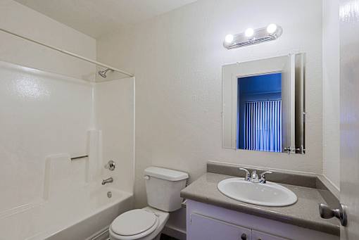 A bathroom with a toilet, sink, and mirror.