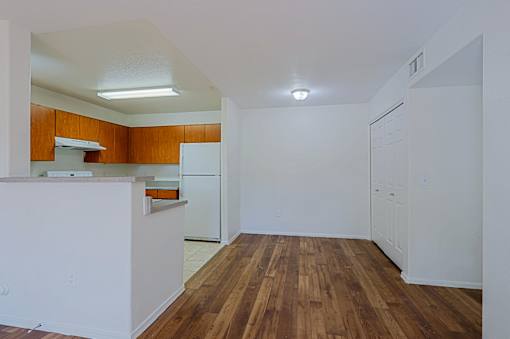 A kitchen with white cabinets and a wooden floor.