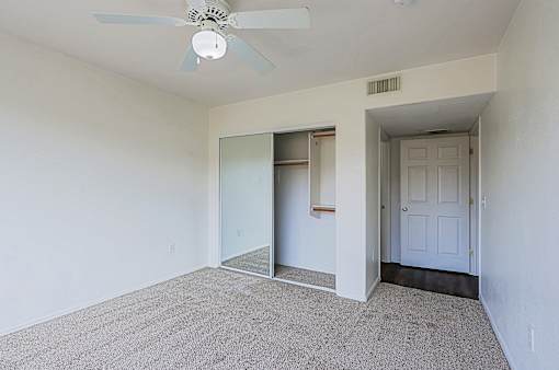 A room with a ceiling fan and carpeted floor.