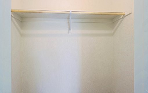 A white closet with a shelf and a hanger.