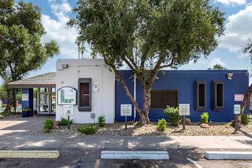 A white and blue building with a tree in front.