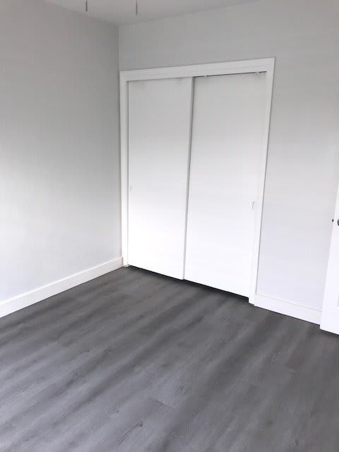 an empty room with white closet doors and a wood floor