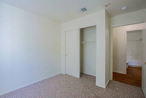 A room with a carpeted floor and a doorway leading to a bathroom.